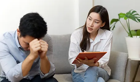 a woman holding a clipboard and a man sitting on a couch