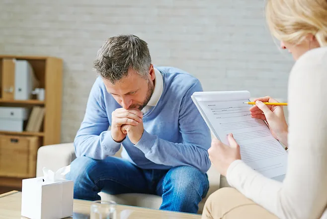 a man sitting on a couch looking down at a paper