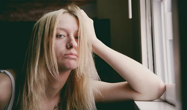 a woman with blonde hair leaning on a window sill