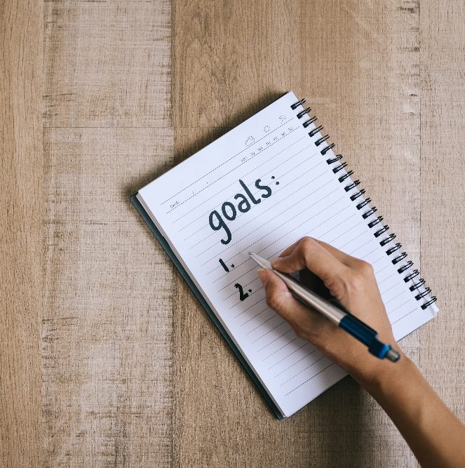 person writing goals on a notepad